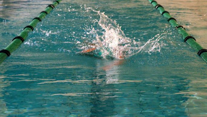 健康的游泳者在游泳池中用慢动作向前划水