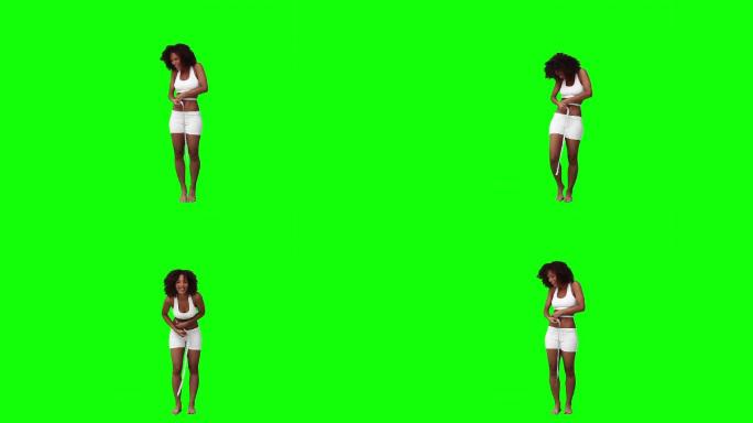一个非洲女性测量腰围，在绿色背景下