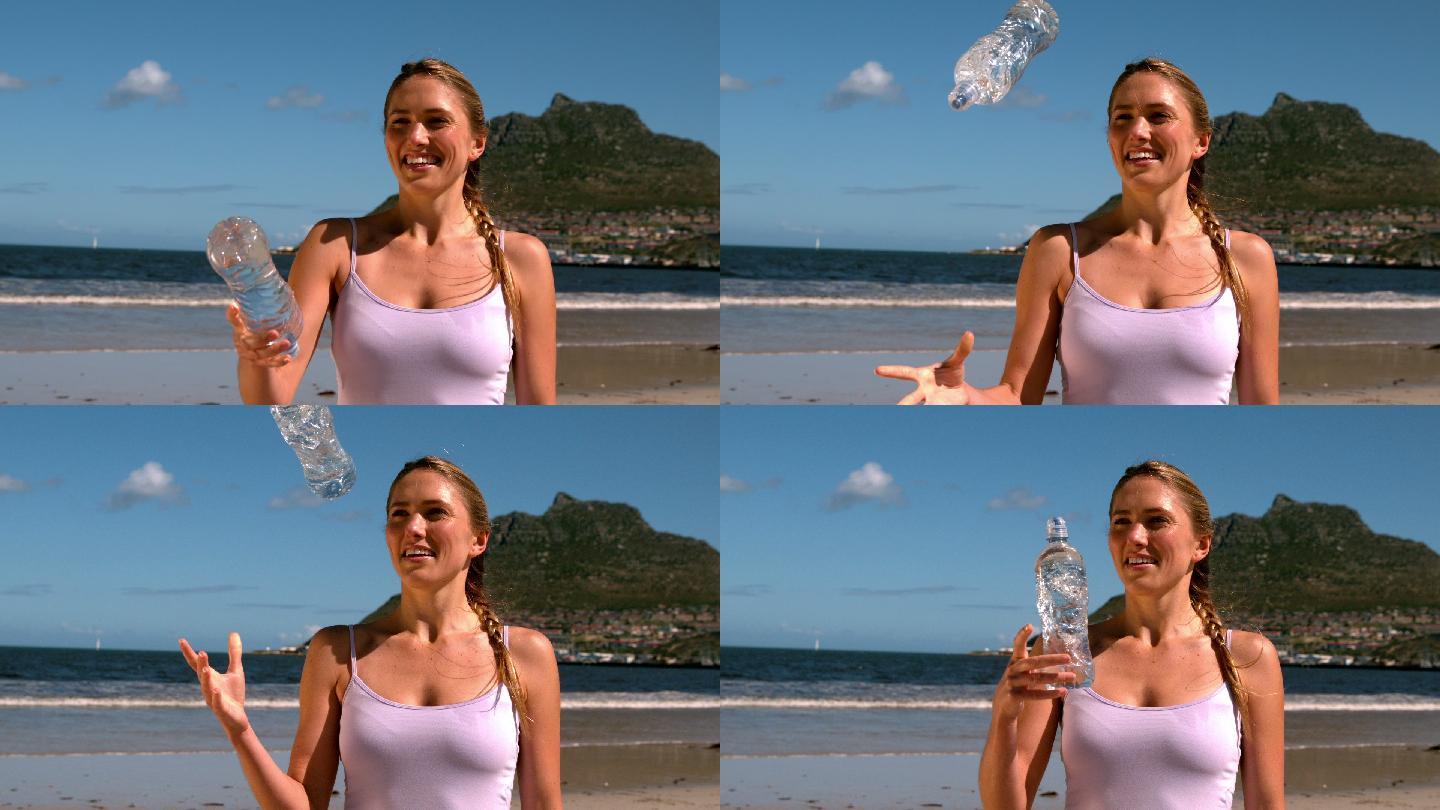 金发美女微笑着把瓶子扔在沙滩上的慢镜头