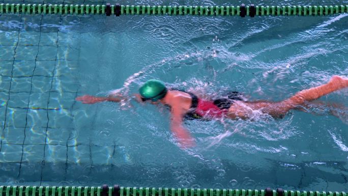 健身女游泳运动员在休闲中心的游泳池里做前划动作