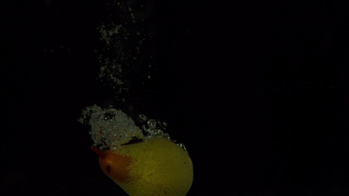 在慢镜头的黑色背景下，梨子跳入水中
