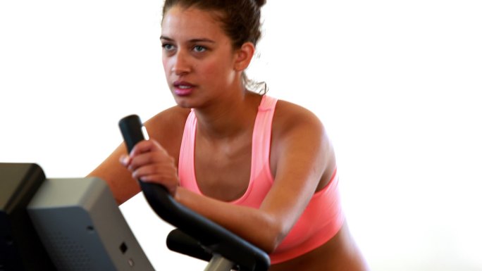 身材苗条的黑发女子在健身房的健身自行车上锻炼