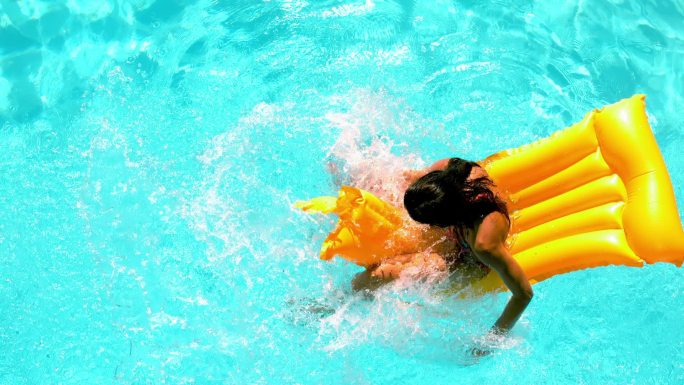 褐发女人用慢动作在游泳池里溅起水花