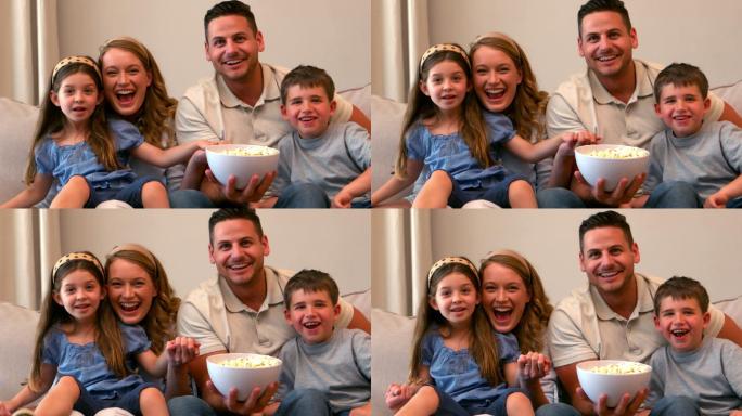 幸福的一家人看电视吃着慢镜头的爆米花