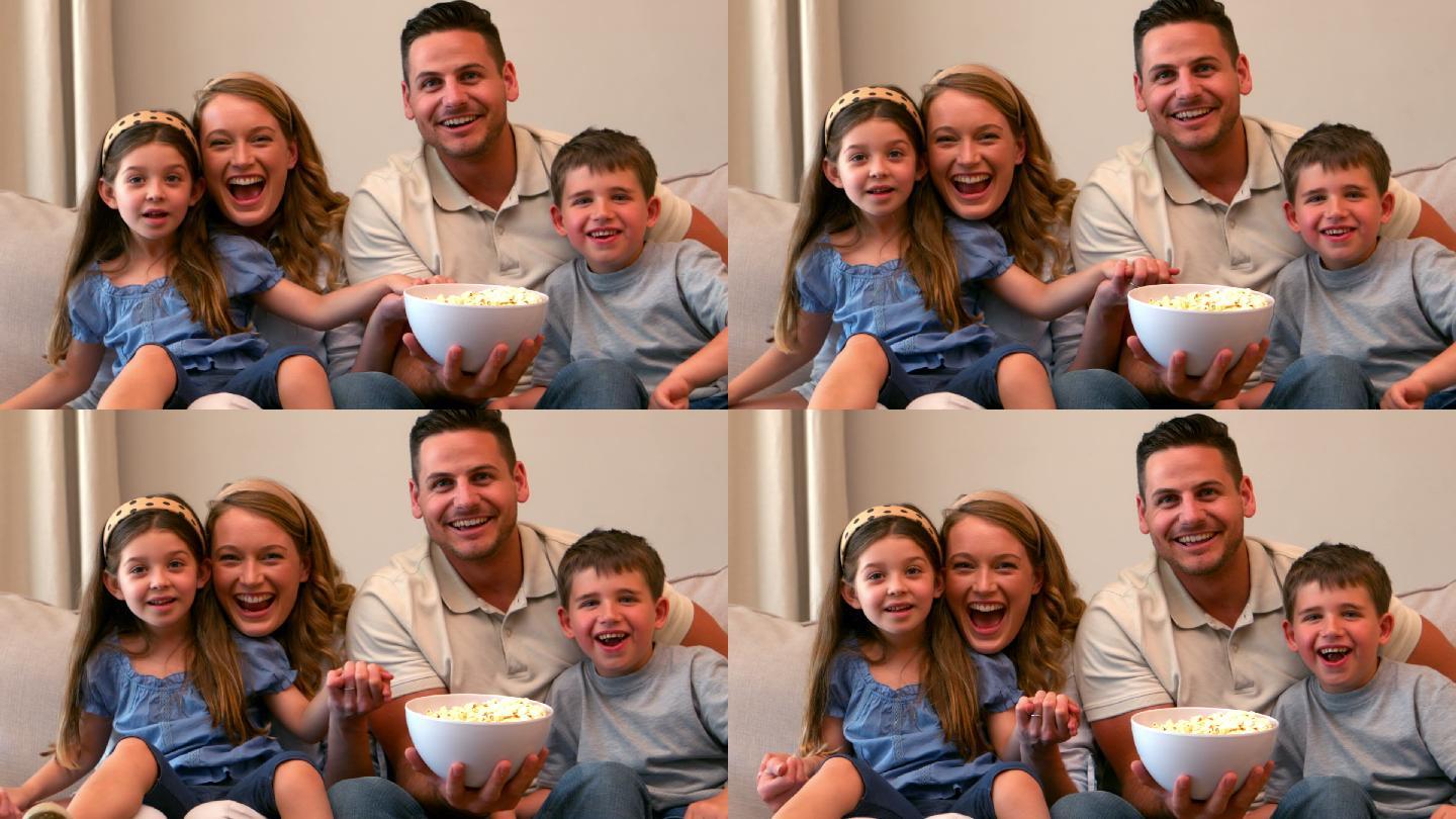 幸福的一家人看电视吃着慢镜头的爆米花