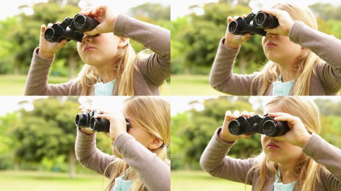 可爱的小女孩在一个阳光明媚的日子里在公园里用望远镜