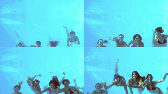 四个朋友在度假时跳进游泳池挥手