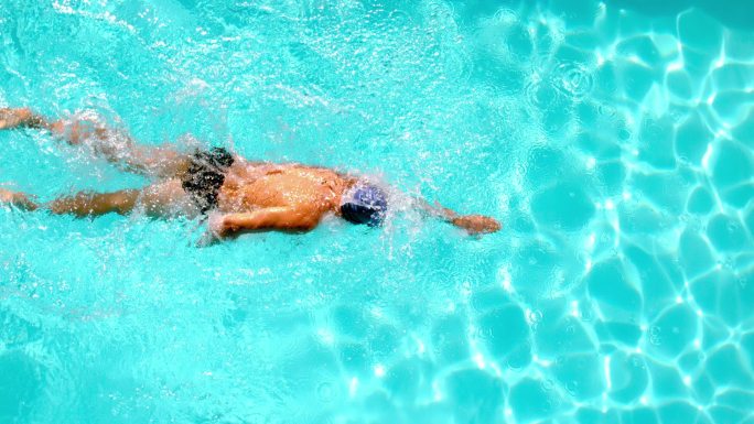 竞技游泳运动员以慢动作游过头顶上的游泳池