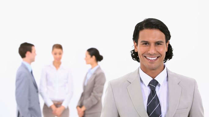 微笑的商人和他的同事站在他身后，背景是白色