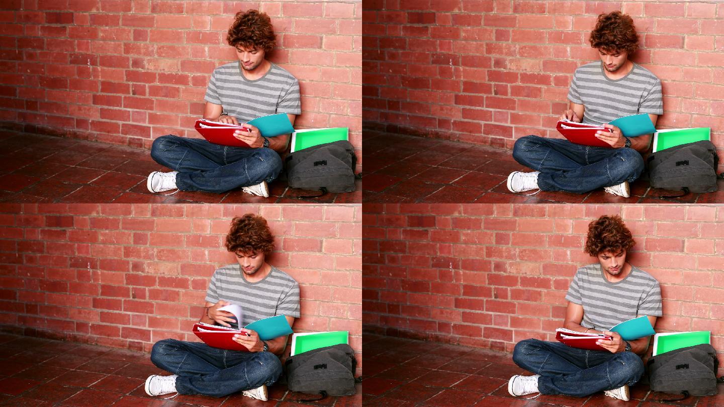 在大学里，一个学生靠着墙坐着读课本