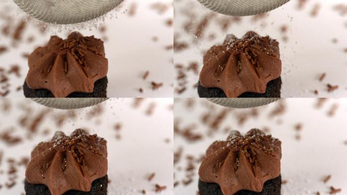 慢镜头中，在巧克力纸杯蛋糕上筛糖霜
