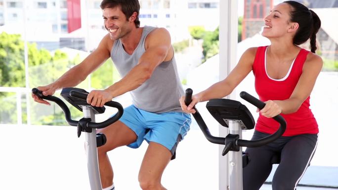 一对情侣在健身房里骑自行车健身
