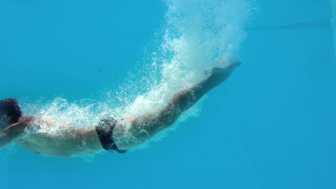 健身男子在游泳池水下慢动作潜水