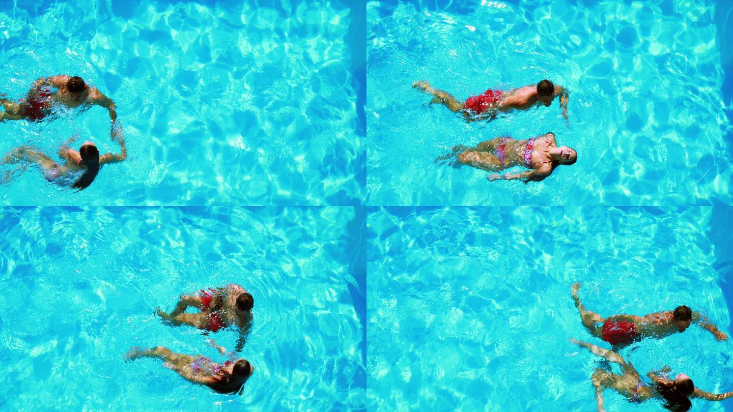 快乐的夫妇在清澈的蓝色游泳池游泳在他们的假期