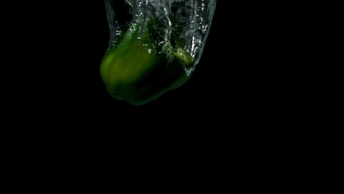 青椒在黑色背景的慢镜头中落入水中