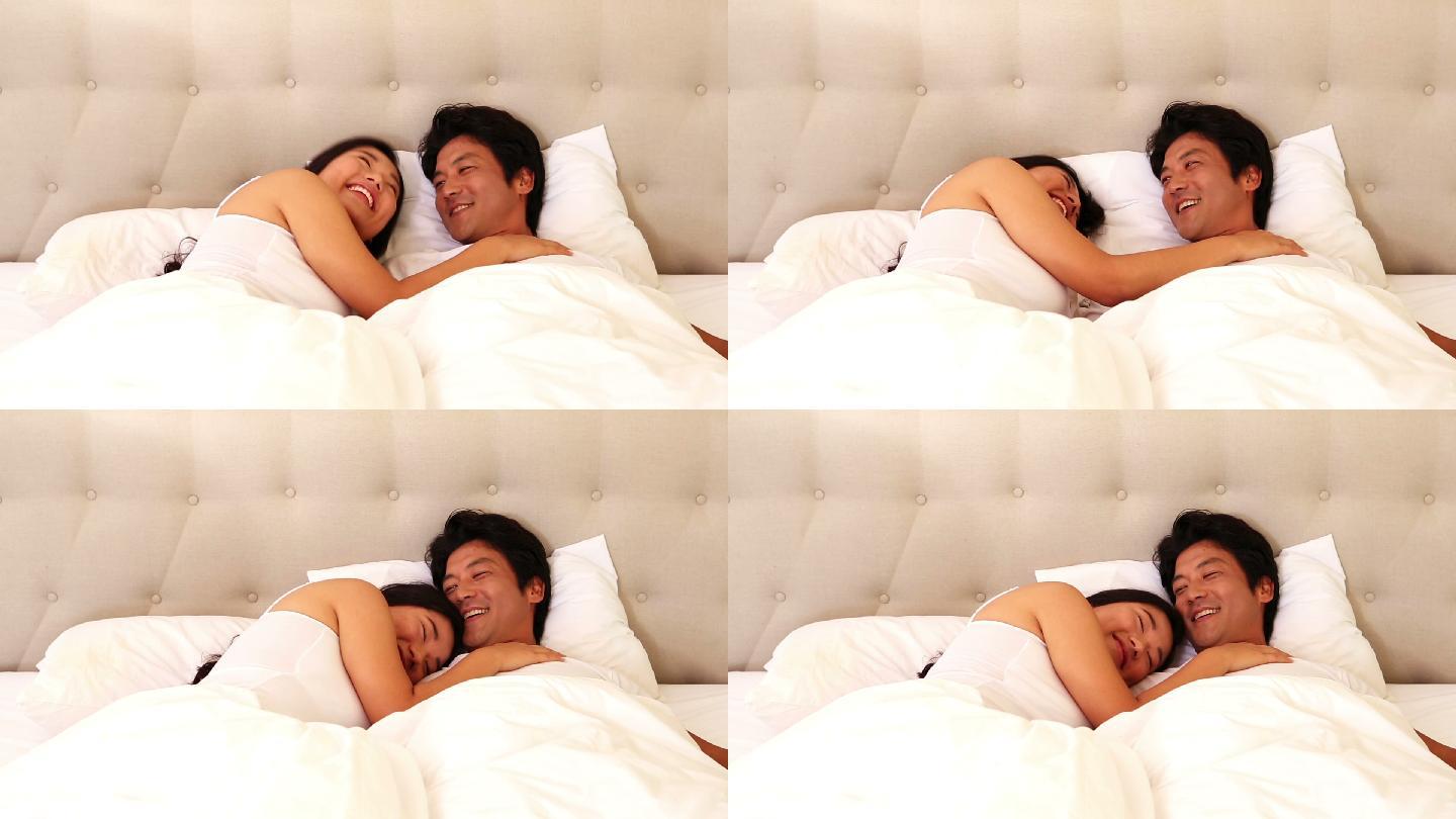 一对相爱的亚洲夫妇躺在卧室的床上