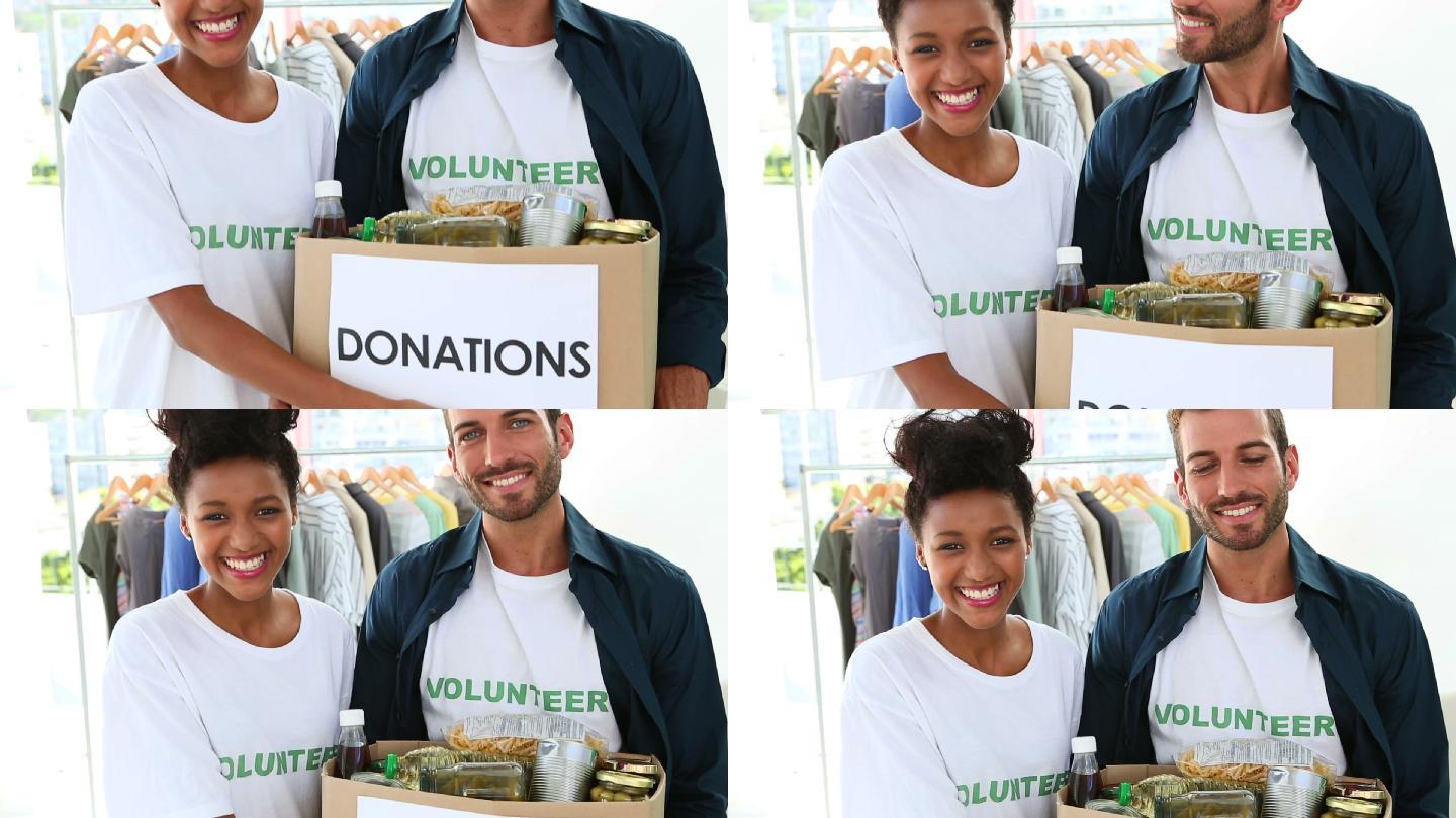 快乐的志愿者队伍拿着食物捐赠箱对着镜头微笑