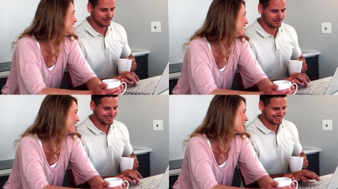 幸福的夫妇在厨房喝咖啡，用笔记本电脑做慢镜头