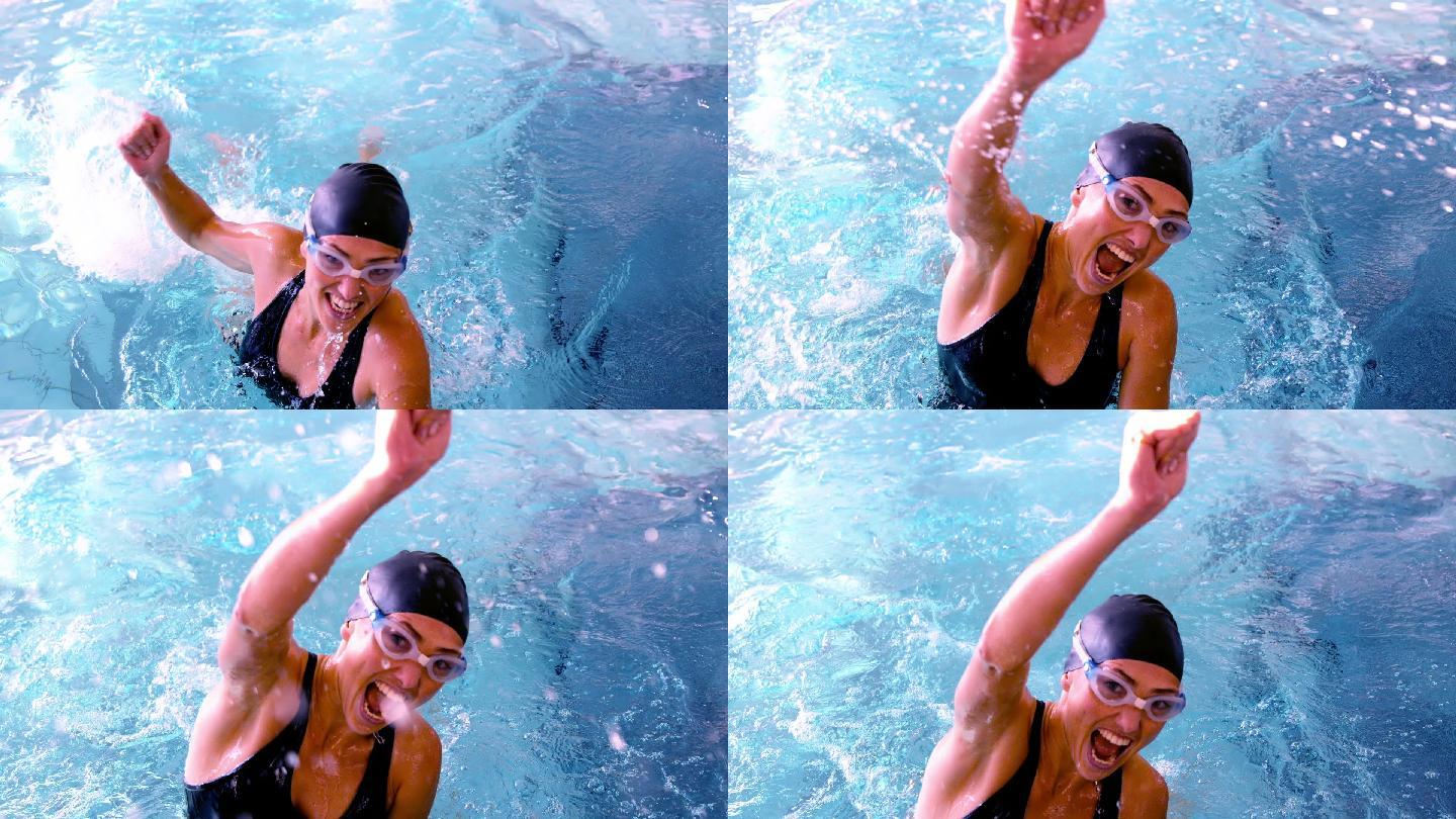 健康的游泳者在游泳池中以慢动作跳起来欢呼