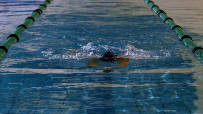 健康的女子游泳运动员在游泳池慢动作蛙泳