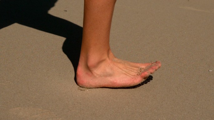 在慢镜头中赤脚在沙滩上跑步的女人