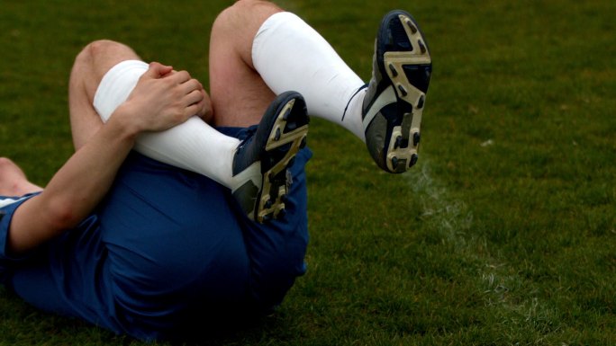 穿蓝色衣服的足球运动员受伤倒地的慢动作