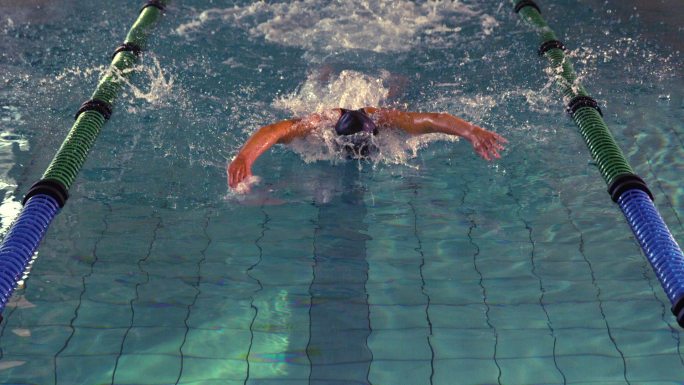 健康的游泳运动员在游泳池里慢动作做蝶泳动作