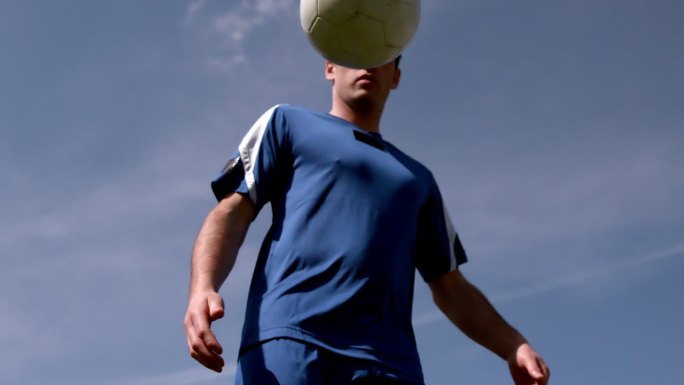 足球运动员在蓝天下用慢动作控制着球