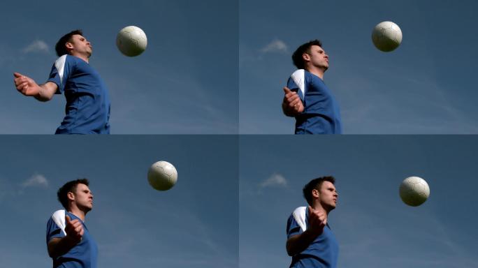 足球运动员在蓝天下用慢镜头用胸触球