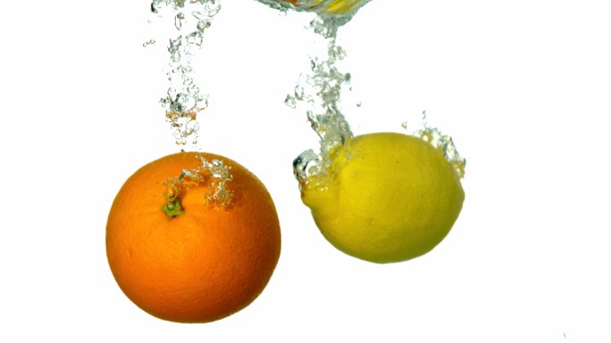 在慢镜头中，橙和柠檬在白色背景下坠入水中