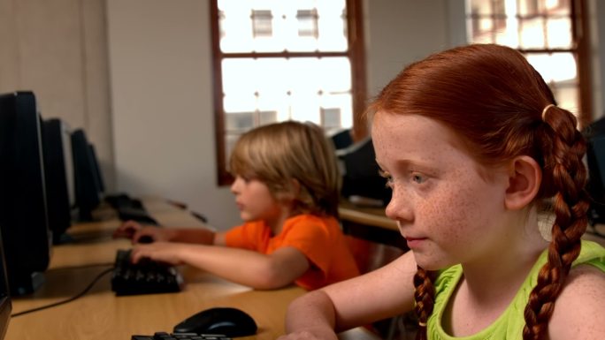 小女孩在学校教室里使用电脑的慢镜头