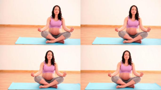 一名孕妇在健身房里的运动垫子上冥想