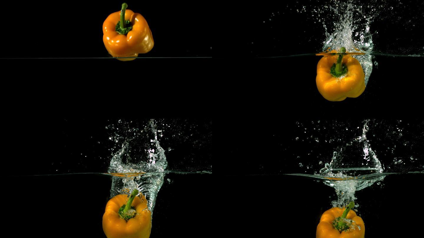 在黑色背景的慢镜头中，黄椒落在水中