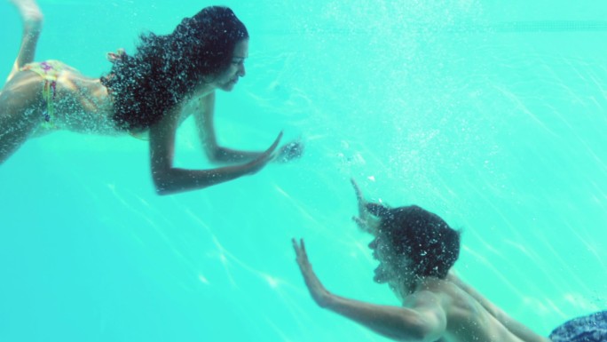 一对快乐的情侣在度假时一起跳进游泳池