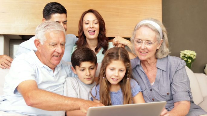 快乐的大家庭在客厅的沙发上一起使用笔记本电脑