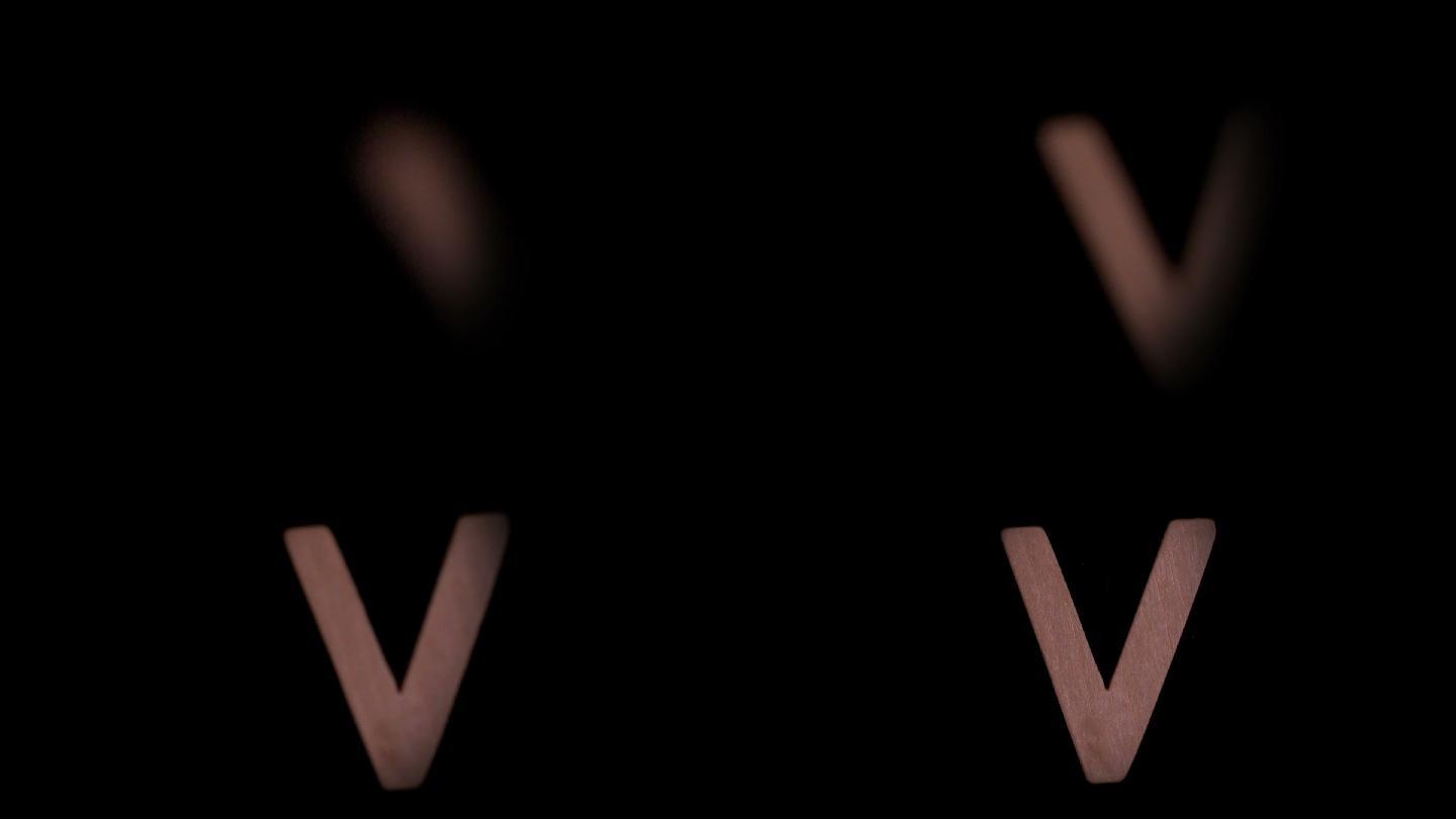 在慢镜头中，字母v在黑色背景上升起