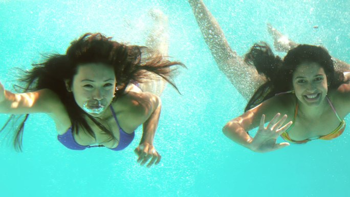 快乐的朋友们在水下用慢镜头向镜头挥手