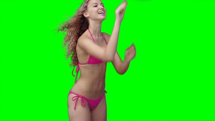 一个穿着比基尼的女人在绿色背景下用一个沙滩球