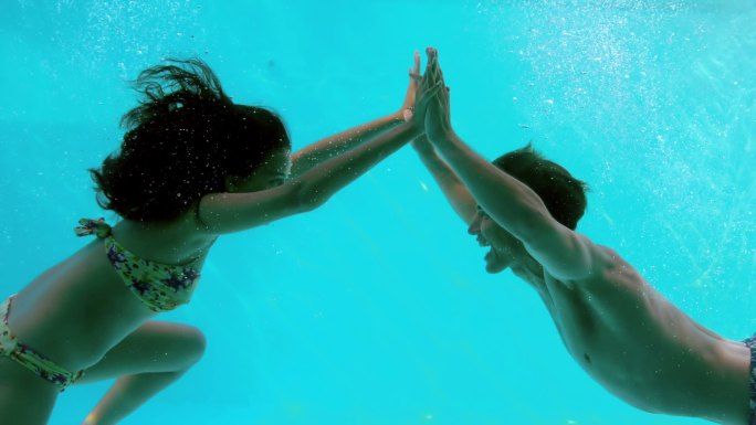 在慢镜头中，一对幸福的夫妇在游泳池里牵着手