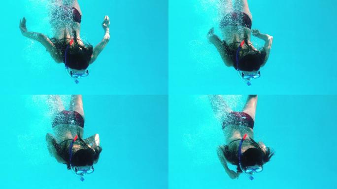 褐发女子在水下穿着通气管慢动作游泳