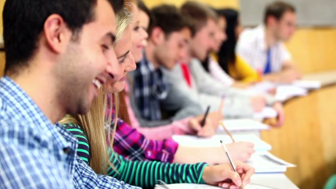 在大学的讲堂里听讲座的一排学生