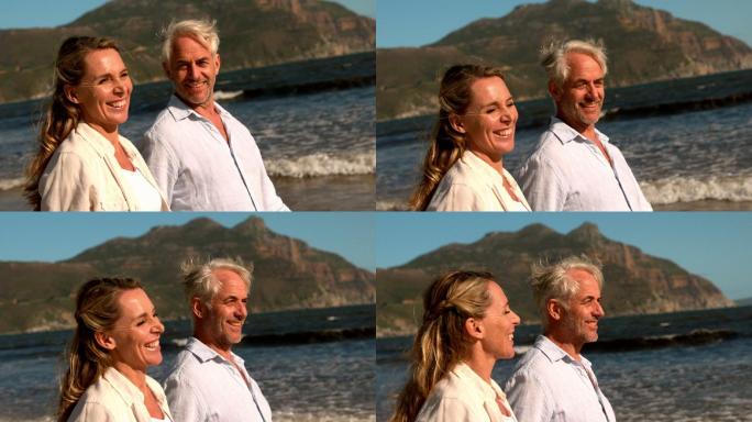 一对成熟的幸福夫妇一起在海滩上慢镜头散步