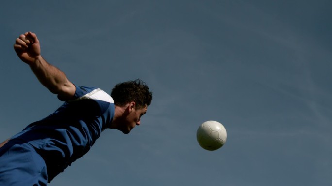 足球运动员在蓝天下用头顶球的慢动作