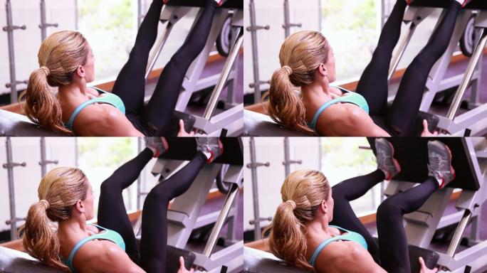 超级健康的女人在健身房使用腿部举重机
