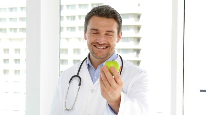 医生在医院的办公室里拿着一个青苹果