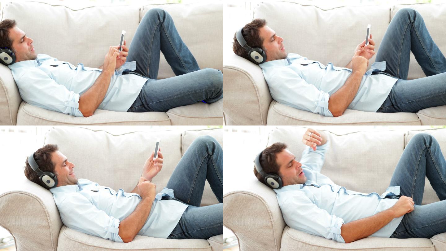 一个男人躺在沙发上，在客厅里听音乐