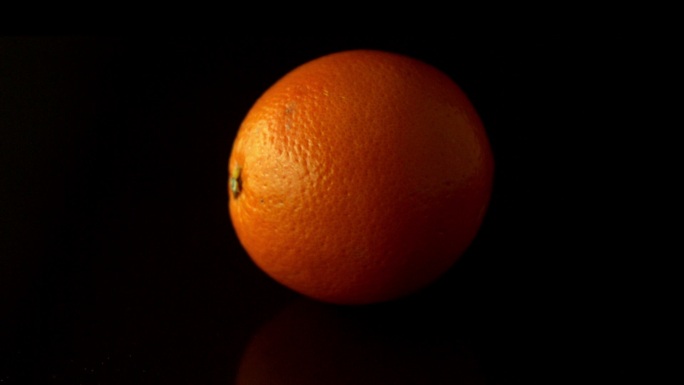 在慢镜头中，橙色在黑色表面上旋转