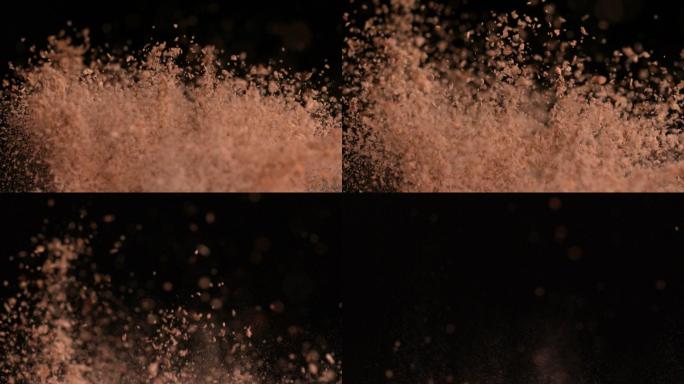 在慢镜头中，棕色面粉在黑色背景下弹跳