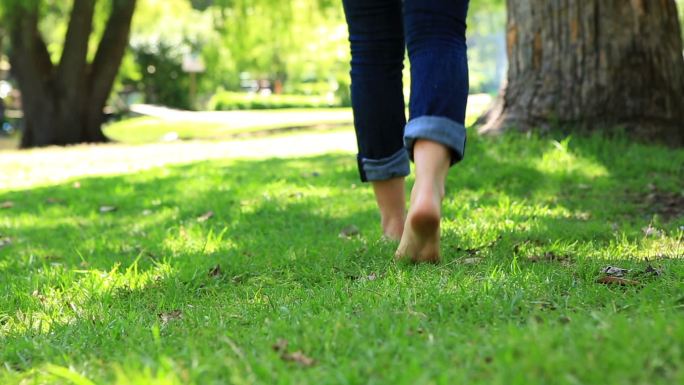 在一个阳光明媚的日子里，一个女人赤脚走在草地上