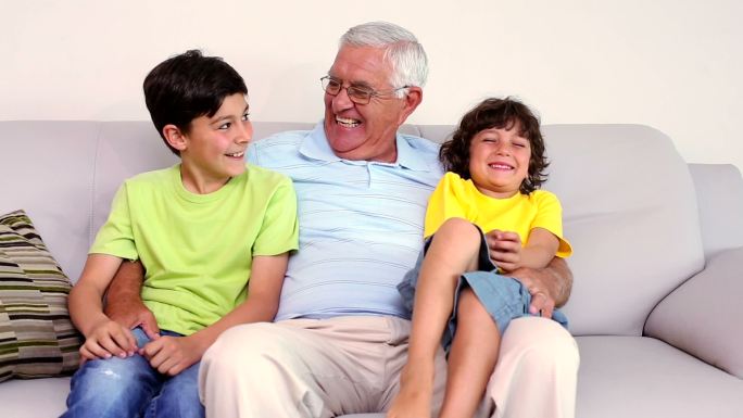 老人和他的孙子坐在客厅的沙发上